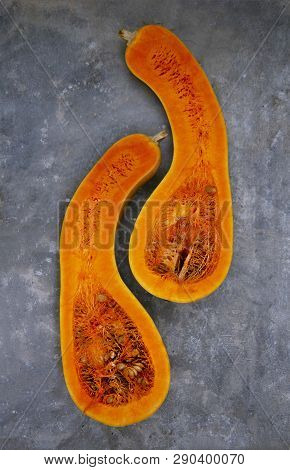 Two Halves Of A Pear-shaped Pumpkin Are Located Vertically Close To Each Other On The Concrete.