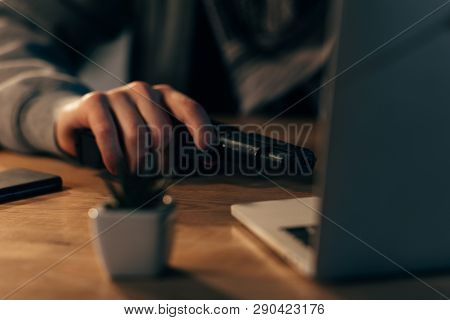 Partial View Of Terrorist With Gun Using Laptop At Table