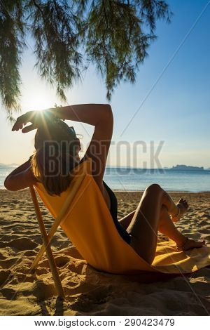 Woman enjoying her holidays on a transat at the tropical beach in Thailand - intentionnal lens flare