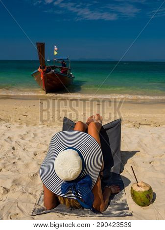 Woman with straw hat enjoying her holidays on a transat at the tropical beach in Thailand