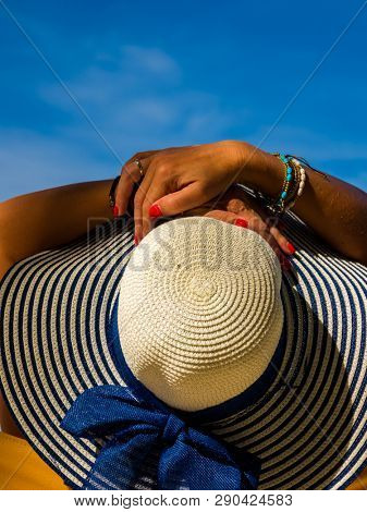 Woman with straw hat enjoying her holidays on a transat at the tropical beach in Thailand