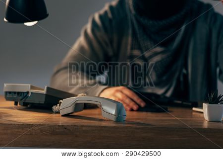 Cropped View Of Terrorist Sitting At Table With Telephone