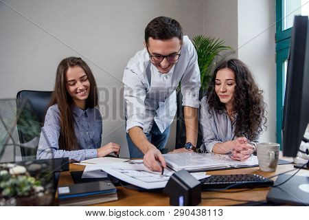 Handsome Firm Manager In Glasses Explains Work Tasks For His Employees. Creative People Or Advertisi