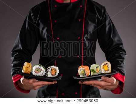Closeup of master chef holding plates with sushi pieces. Concept of asian food