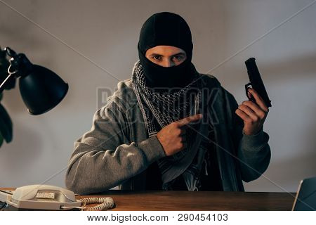 Terrorist In Black Mask Pointing With Finger At Gun