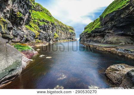 Beautiful View Of Dock Or Harbor With Natural Black Rock And Green Grass In Gjogv Village With Clear