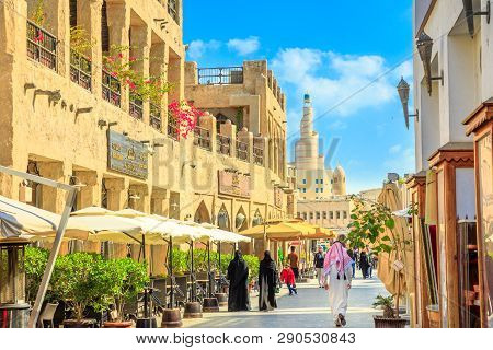 Doha, Qatar - February 20, 2019: Women And Men In Traditional Arab Clothing Walk Along Main Street I