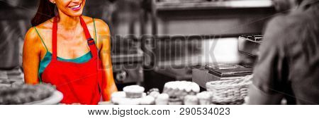 Smiling female staff interacting to customer at counter in bakery shop