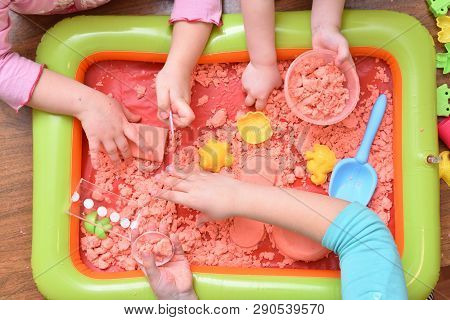 Children Play With Pink Kinetic Sand For Sculpting Figures. Top View, Hands Close Up