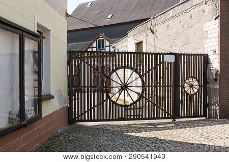 Wooden Gate, Ancient Work With A Decorative Accessory In The Form Of A Round Wheel, In Sunny Summer 