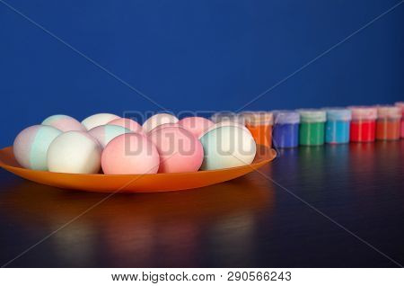 Painted Easter Eggs And Paints On The Table. Preparation For Easter. Wooden Table.
