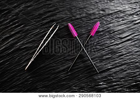 On The Black Background Lies A Pair Of Tweezers And Eyebrow Comb Brush The Top View Copy Space