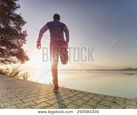 Man Runner Doing Stretching Exercise, Preparing For Morning Workout In The Lake Park. Street Fitness
