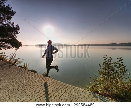 Freeze Sportsman In  Running Pose.  Runner Is Sprinting Along Mountain Lake Within Morning Moody Atm