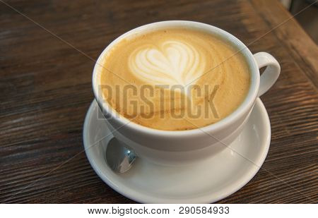 A Cup Of Coffee With A Pattern In The Form Of A Heart On The Milk Foam. The Big Cup Of Cappuccino Wi