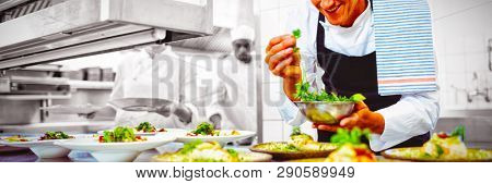 Happy chef garnishing appetizer plates at order station in restaurant