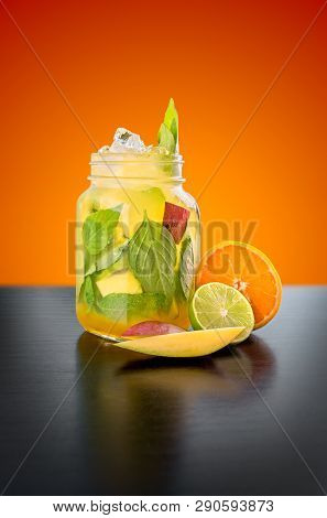 Homemade Mango Basil Lemonade With Orange, Mango And Lime On A Orange Background