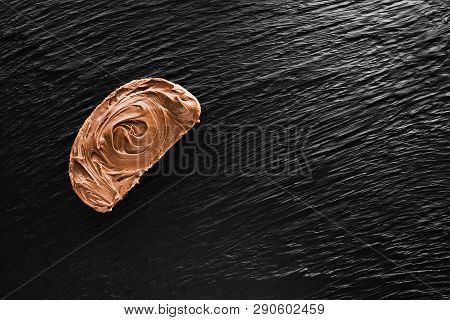 A Piece Of Bread Smeared With Chocolate Paste, On A Black Textured Background Like Mica, A Copyspace