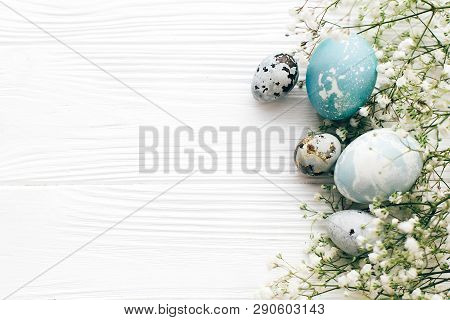 Happy Easter. Stylish Easter Eggs With Spring Flowers Border, Flat Lay On White Wooden Background Wi