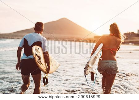 Happy Surfer Couple Running With Surfboards Along The Sea Shore - Sporty People Having Fun Going To 