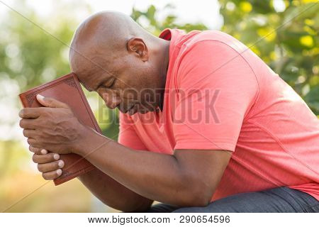African American Man Praying And Reading The Bible.