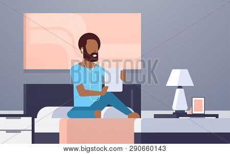 Man Listening Audio Book Through Headphones African Americn Guy Using Tablet Sitting On Bed Modern H