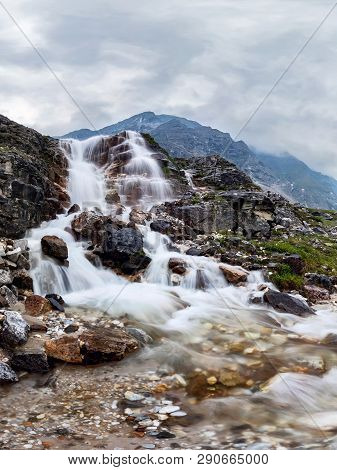 Mountain Waterfall Stream In Misty Rainy Weather In The Valley Flowers