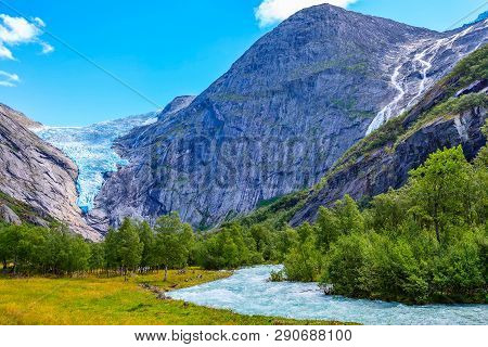 Briksdal Or Briksdalsbreen Glacier In Olden, Norway With Green Mountains, River And Waterfall