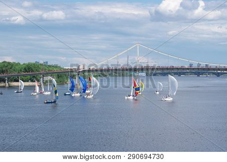 Regatta Competition Of River Sailing Yachts Boats With White And Multicolored Sails, Reflected Sky C