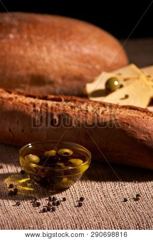 Fresh Bread Baguette With Olive Oil, Olives. Cheese And Rosemary On Wooden Background. Teasty Breakf