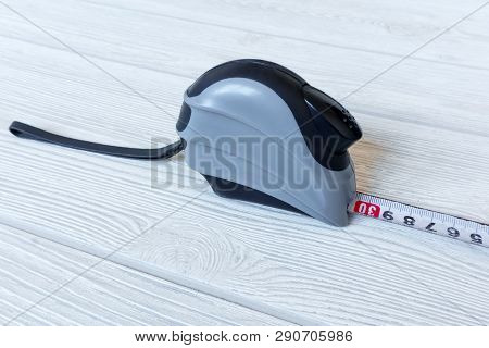 Metric Self-retracting Metal Tape Measure On A Light Wooden Surface