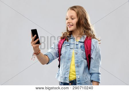 education, school and people concept - happy smiling teenage student girl with bag taking selfie by smartphone over grey background