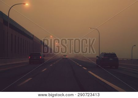 Highway In Mystic Fog Mist Smog. Cars On Freeway Road At Evening In American City Country. Poor Visi