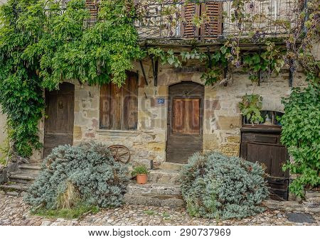 Najac, Midi Pyrenees, France - September 16, 2017: Old Stone Facade With Several Wooden Doors Surrou