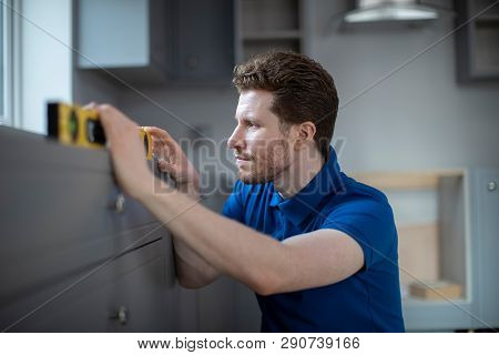 Carpenter With Level Installing Luxury Modern Fitted Kitchen