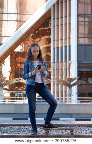 Happy Teen Girl Look At Mobile Phone On A Big Street