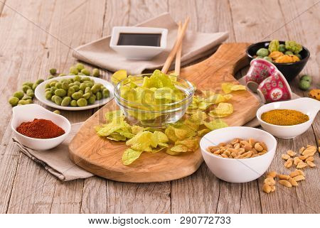 Wasabi Flavour Potato Crisps On Wooden Table.