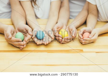 Four Colored Easter Eggs In Mother Father Sister And Brothers Hands Like In The Nests. Blurred Backg