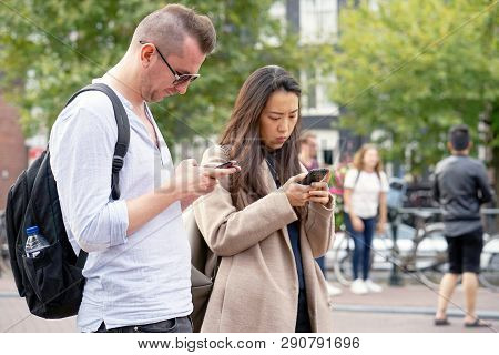 Hip Young Couple Looking At Smartphone On Shopping Trip On A Sunny Day In The City. Beautiful Young 