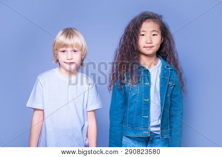 Interracial Children. Two Children Of Caucasian And Asian. Blond Boy And Brunette Girl. On A Blue Ba