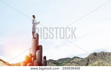 Young Female Doctor With Folder In Hands Satnding On Stone Column