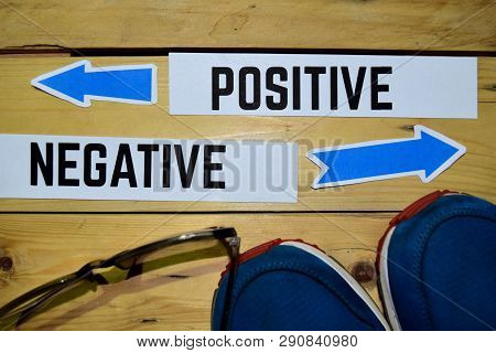 Positive Or Negative Opposite Direction Signs With Sneakers And Eyeglasses On Wooden Vintage Backgro