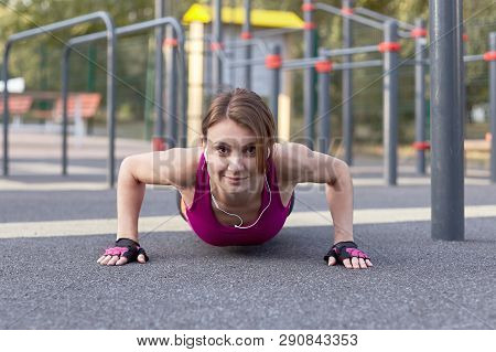 Gorgeous Slim Young Woman In Fitness Activity On Outdoor Sportsground, Pushes Ups And Down. Front Vi