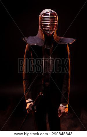 Man In Suit And Kendo Helmet Holding Bambo Sword On Black