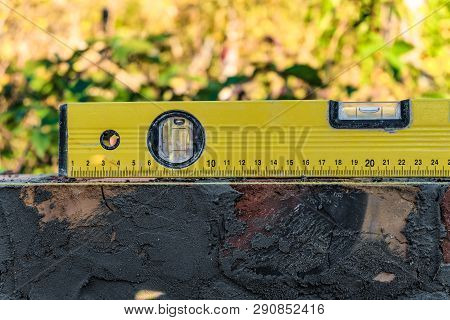 Yellow Bubble Level Lies On Brick Masonry Wall. Bubble Centered.