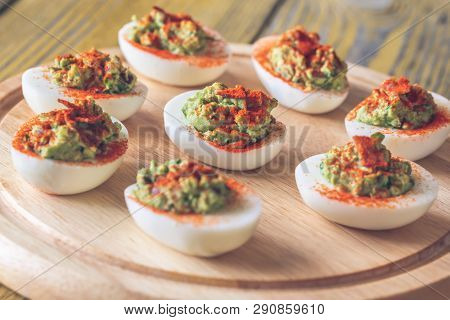 Guacamole And Bacon Deviled Eggs On Cutting Board