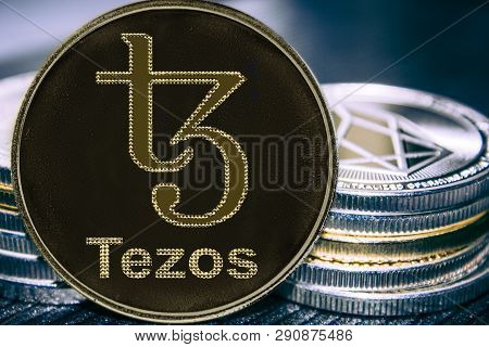 Coin Cryptocurrency Tezos On The Background Of A Stack Of Coins. Xtz Coin.