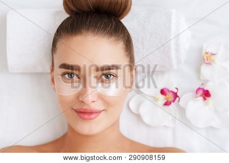Woman With Collagen Pads Under Her Eyes In Spa Salon, Top View