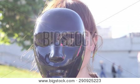 Portrait Of A Young Pretty Charismatic Woman Who Hiding Her Face Behind The Black Mask And Then Sets