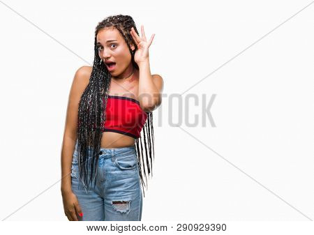 Young braided hair african american with pigmentation blemish birth mark over isolated background smiling with hand over ear listening an hearing to rumor or gossip. Deafness concept.